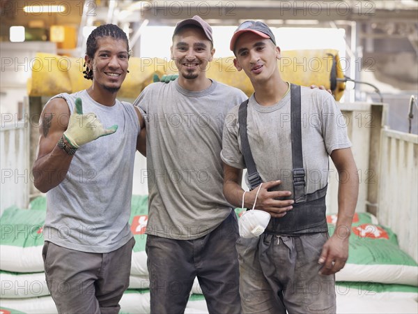 Hispanic workers hugging in factory