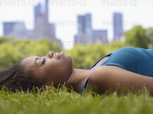 African woman laying on grass in park