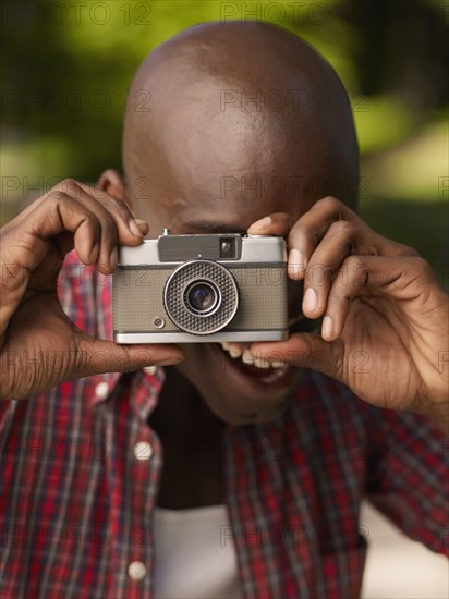 African man taking photograph with retro camera