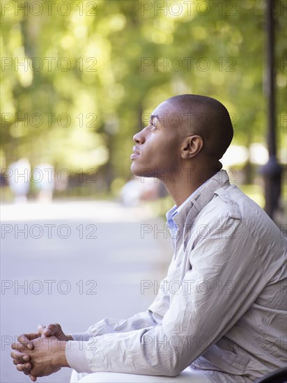 African man looking up with hands clasped