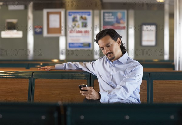 Mixed race man looking down at cell phone