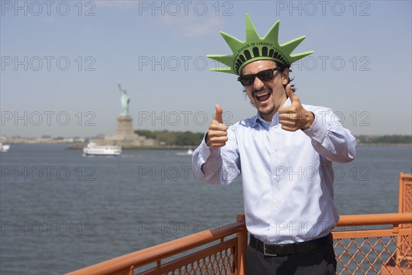 Mixed race businessman on ferry wearing Statue of Liberty hat