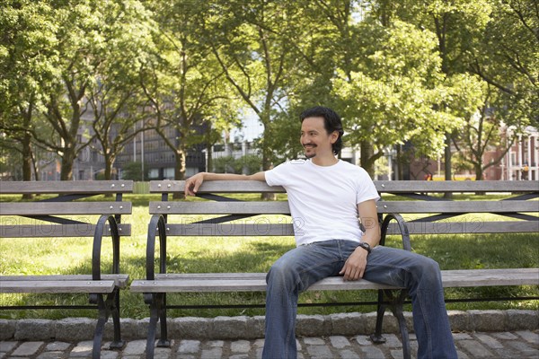 Mixed race man relaxing on park bench