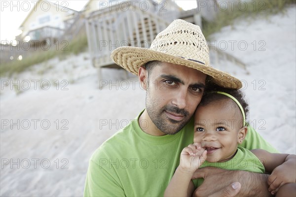 Father holding daughter on beach