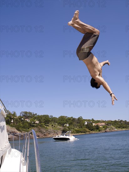 Hispanic man jumping from sailboat