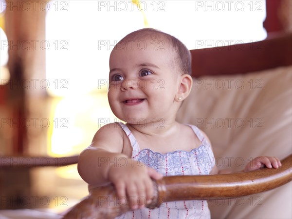 Hispanic baby girl sitting in chair