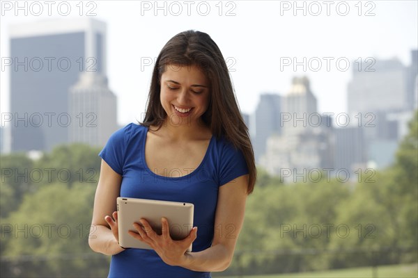 Caucasian woman using digital tablet in city park