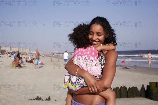 Mixed race mother and daughter hugging at the beach