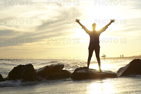 Black woman with arms raised on beach