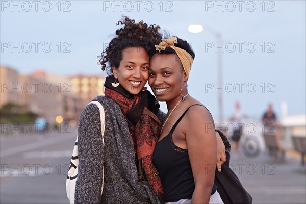 African American friends hugging on sidewalk