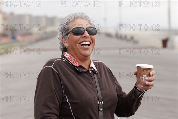 Smiling woman drinking coffee on boardwalk