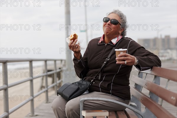 Women eating pastry and drinking coffee on boardwalk