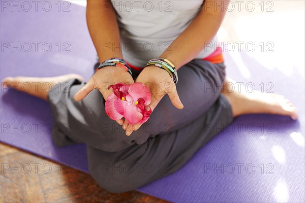 Mixed race woman with flowers on yoga mat