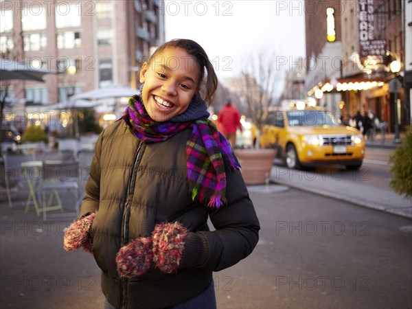 Mixed race girl smiling on city street