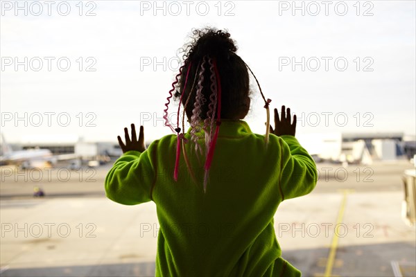 Mixed race girl looking out airport window