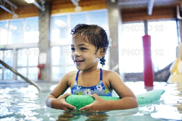 Mixed race girl using floater in swimming pool