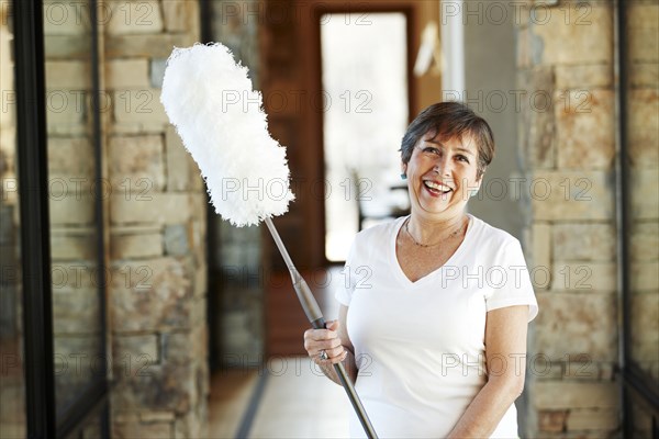 Smiling Hispanic woman holding duster