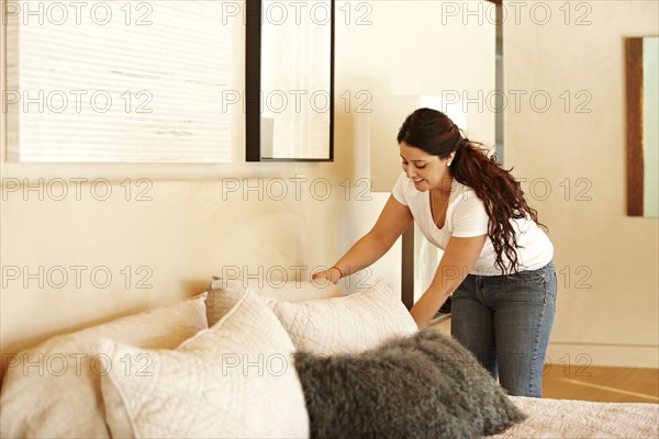 Hispanic woman making bed