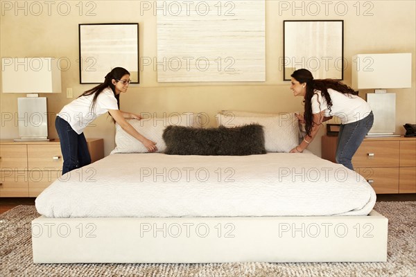 Hispanic women making bed