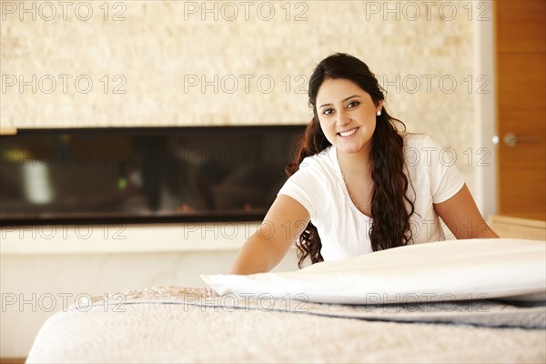 Hispanic woman making bed