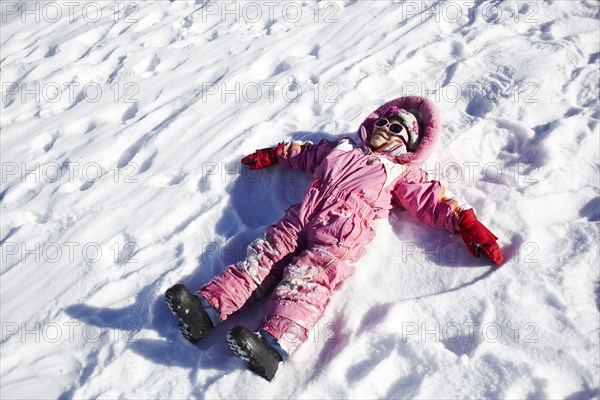 Mixed race girl making snow angels