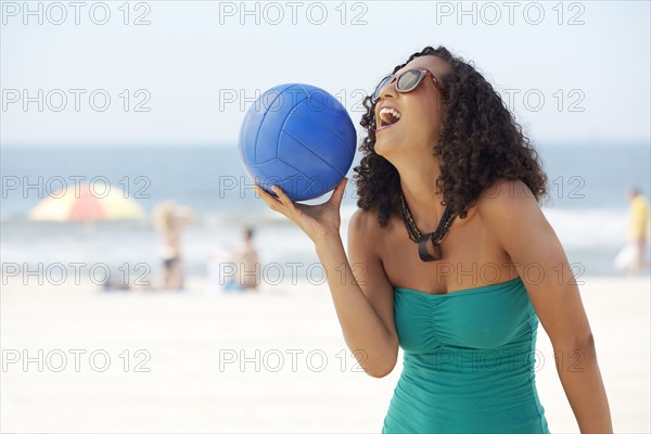 Mixed race woman with volleyball on beach