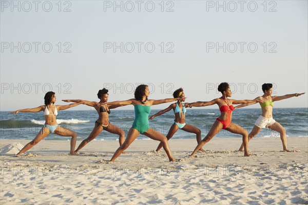 Women practicing yoga on beach