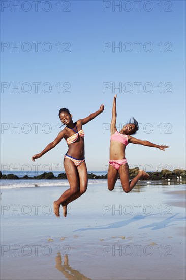 Black women jumping for joy on beach