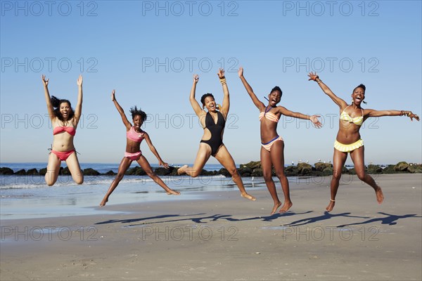 Women jumping for joy on beach