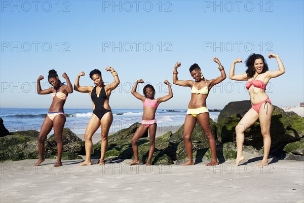 Women flexing muscles on beach