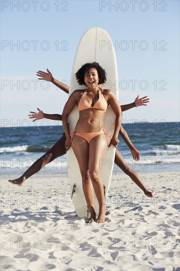 Friends posing with surfboard on beach