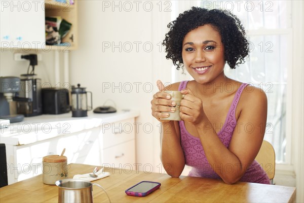 Mixed race woman drinking coffee in kitchen