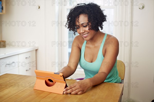 Mixed race woman using digital tablet in kitchen