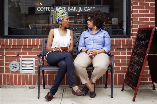 Women talking outside coffee shop on city street