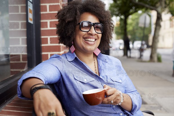 Woman having coffee on city street