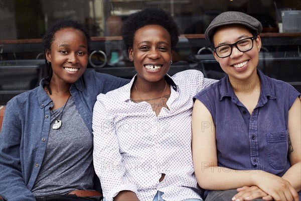 Women smiling outside coffee shop on city street