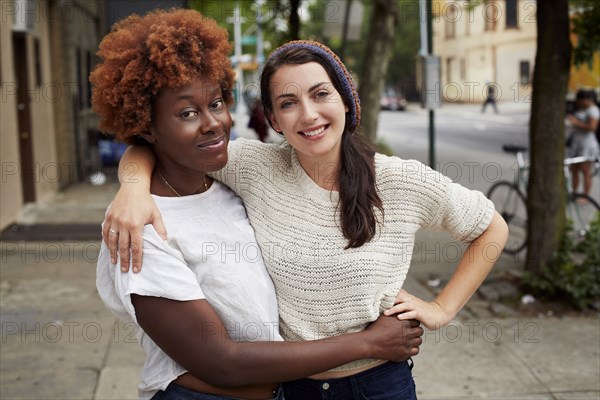 Women hugging on city street