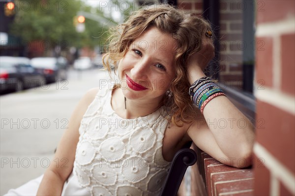 Caucasian woman sitting on bench on city street