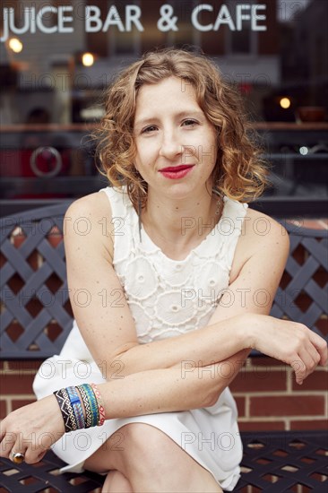 Caucasian woman sitting outside coffee shop on city street