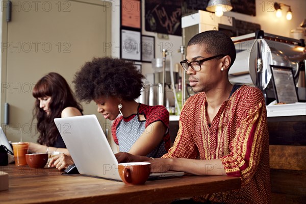 People using technology in coffee shop