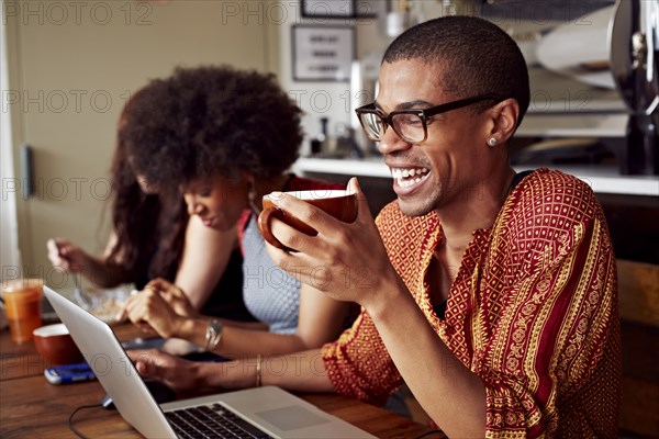 People using technology in coffee shop