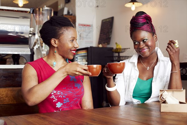 Women toasting each other with coffee in cafe