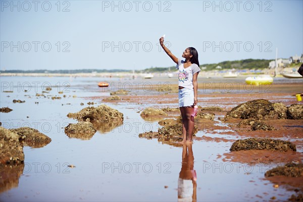 Black teenage girl taking selfie on beach