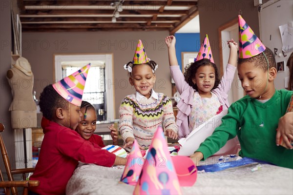 Children wearing party hats and celebrating at table