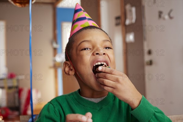 Black boy eating cake at party