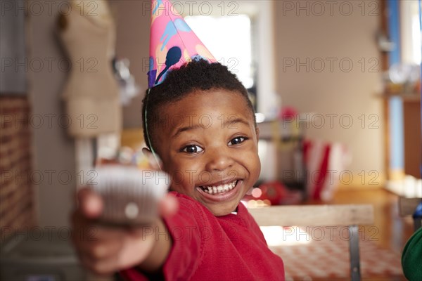 Black boy offering cupcake at party