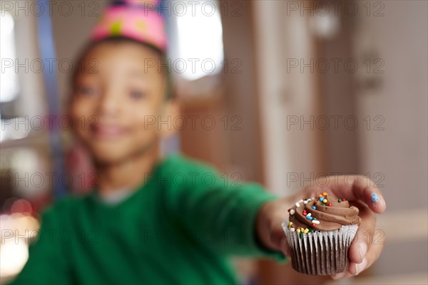 Black boy offering cupcake at party