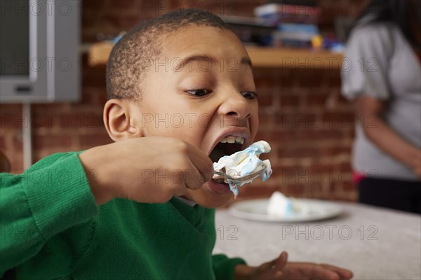 Black boy eating cake at table