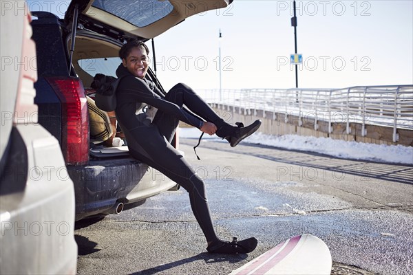 Black teenage girl putting on wetsuit