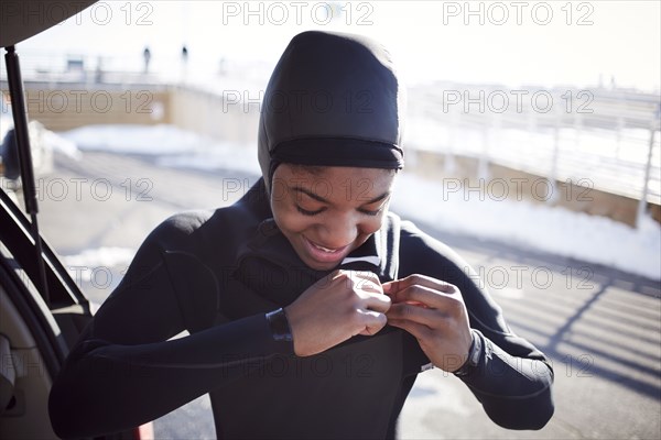 Black teenage girl putting on wetsuit